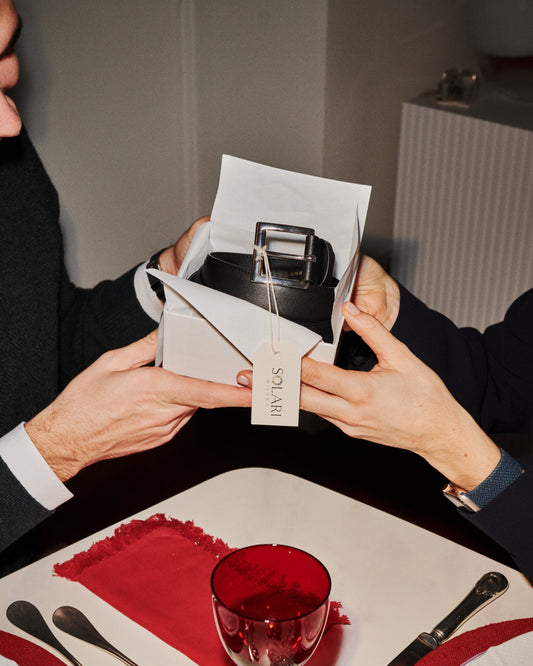 Two people exchanging a gift box at a dining table, featuring a stylish watch inside.